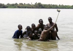 A group of young men use a selfie stick to take a picture of themselves in shallow waters known as the first cataract of the River Nile outside Khartoum, Sudan, May 22, 2015. In Sudan, which faces insurgences in the western region of Darfur and along its border with breakaway South Sudan, as well as double-digit inflation and high unemployment, life goes on for young people in the capital Khartoum. REUTERS/Mohamed Nureldin Abdallah