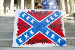 Jay Bender holds a sign asking for the removal of the confederate battle flag that flies at the South Carolina State House in Columbia, SC June 20, 2015.  REUTERS/Jason Miczek - RTX1HF36