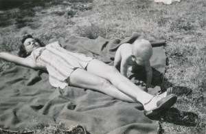 Beautiful woman sunbathing with a naked baby, ca. 1940s