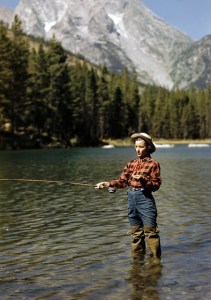 Young cowgirl Esther Allen trout fishing in String Lake. Teton Mountains behind.