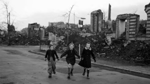 Three girls skate home from school, past blocks of houses destroyed by Allied air raids, Essen, Germany, February 14, 1949
